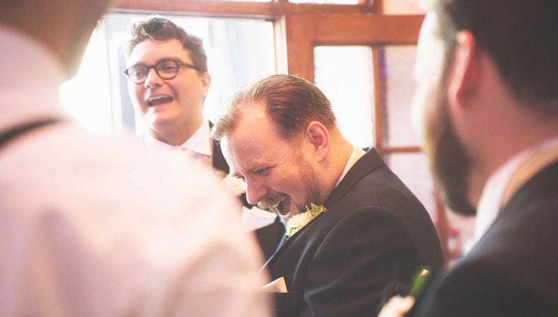 Groomlaughing in astonishment at a magic trick during a gay wedding