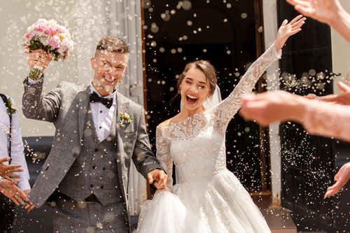 A bride and groom having confetti thrown at them at their magical wedding